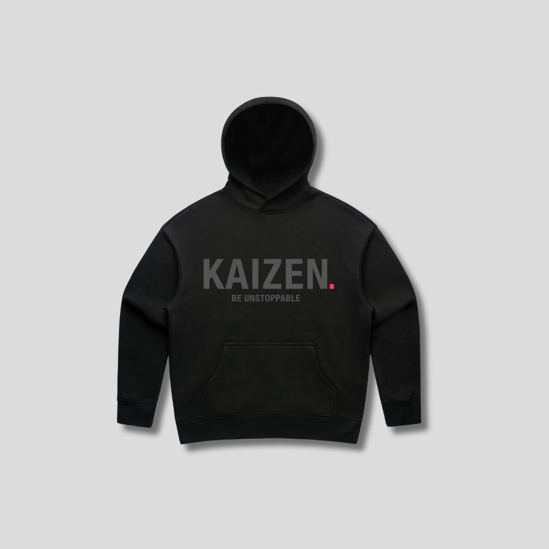 Black hoodie with 'KAIZEN' text, folded flat on grey background